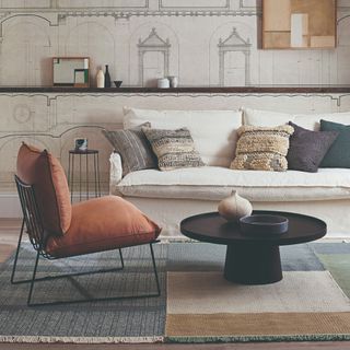 A living room with an architectural wall mural and a skirted cream sofa with contrasting cushions