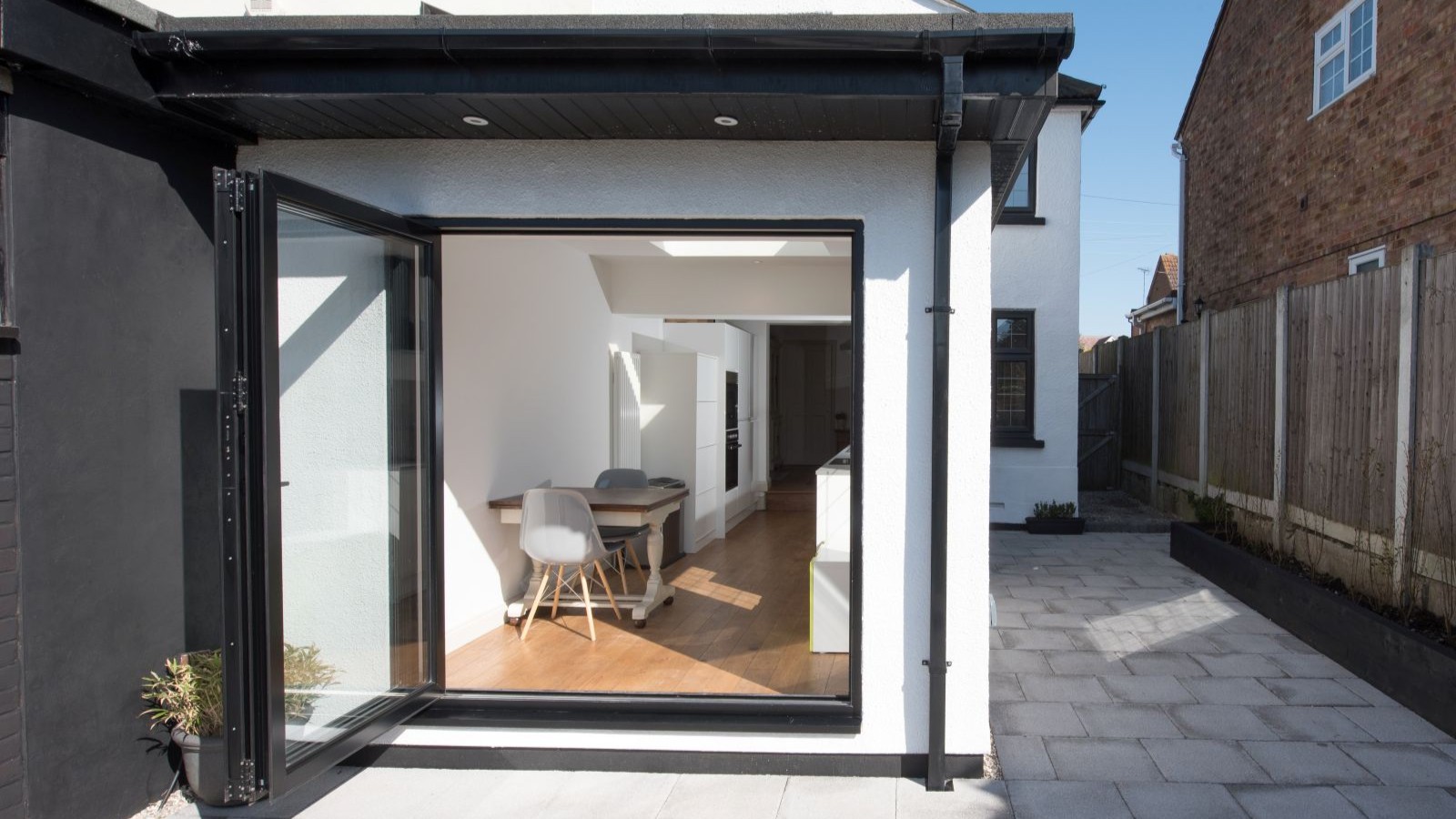A white rendered kitchen extension with a large glass door that opens out on to a patio