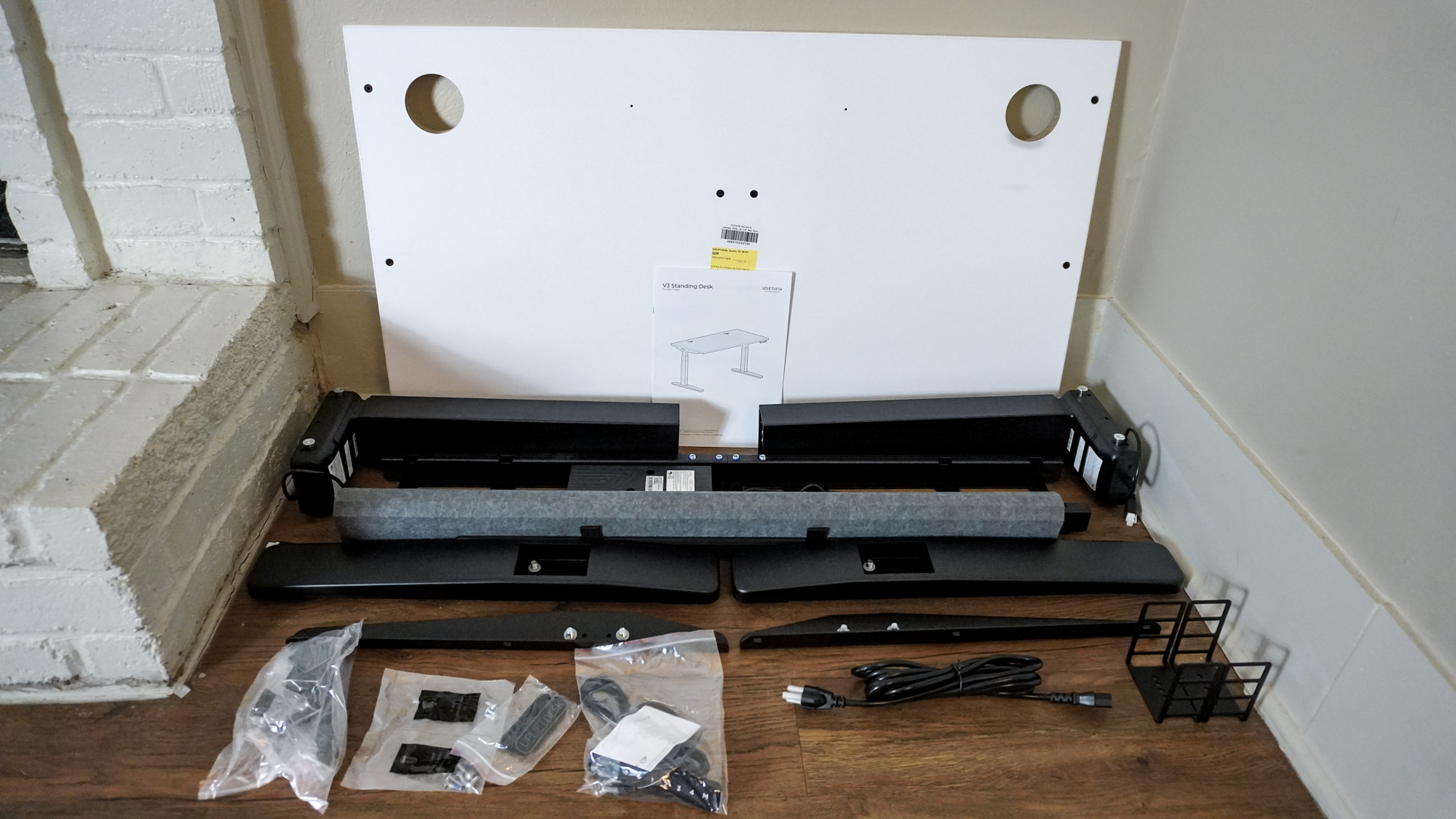 The Uplift V3 standing desk unboxed with all of the parts stacked in a corner