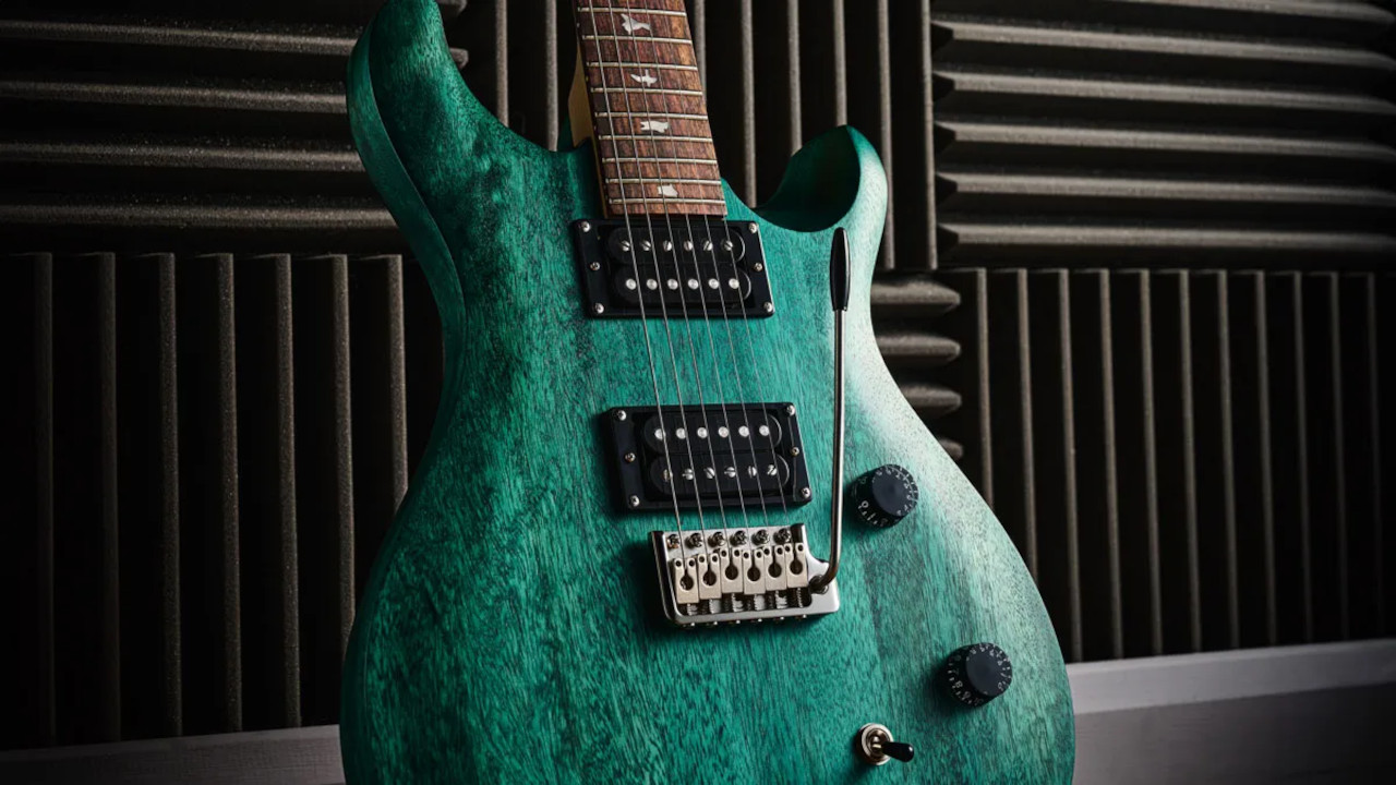 A close-up shot of the PRS SE CE 24 Standard Satin in turquoise leaning against a studio wall.