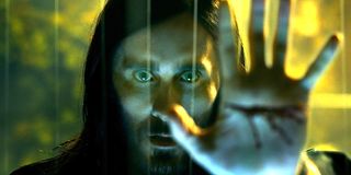 Morbius (Jared Leto) puts his bleeding hand on a glass wall and stares into the camera.