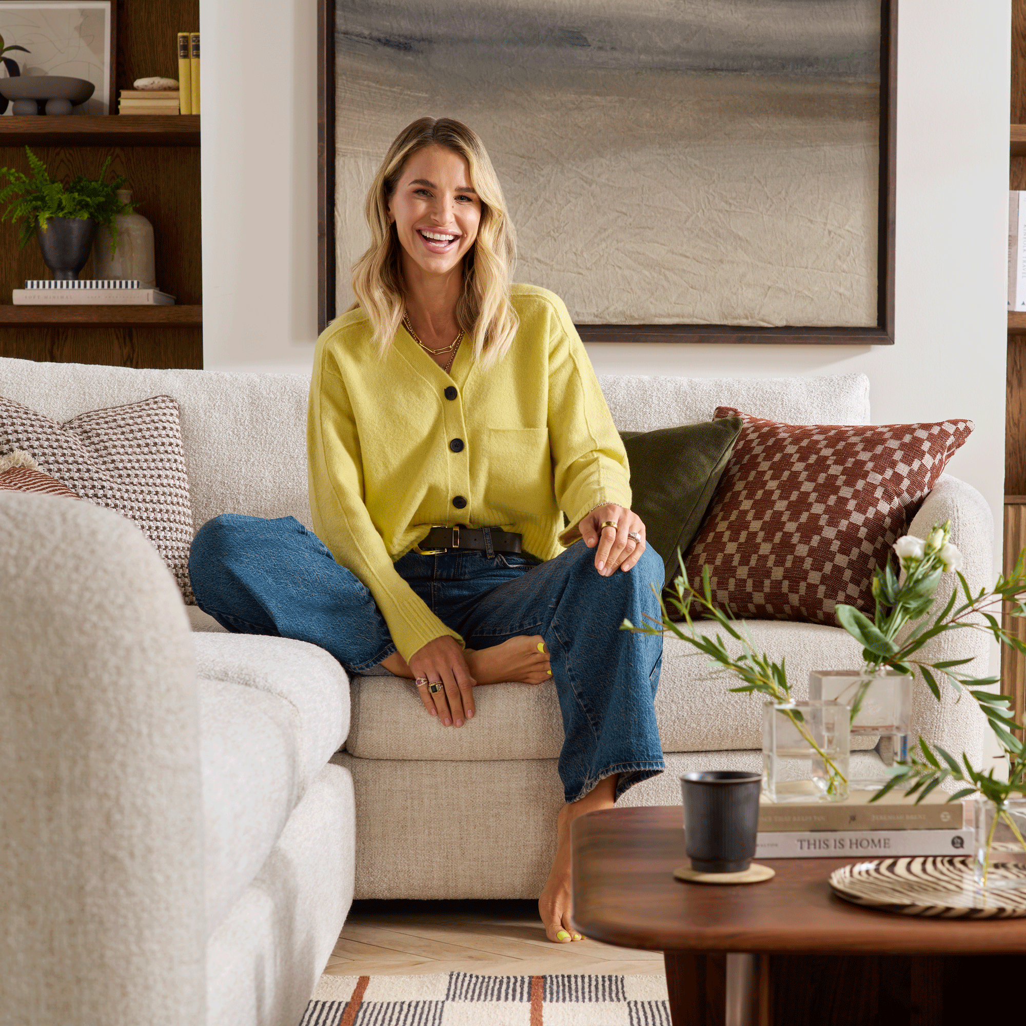 Vogue Williams in a living room sitting on a cream boucle corner sofa
