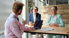 Credit union customers chat with a banking professional at a table in a credit union.