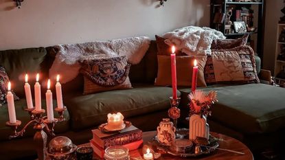 A dark living room with a green couch, candles, and books