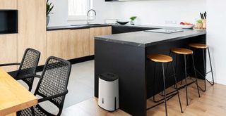 Black and wooden kitchen with a dehumidifier to show how a dehumidifier works to beat steam and humidity levels in any room