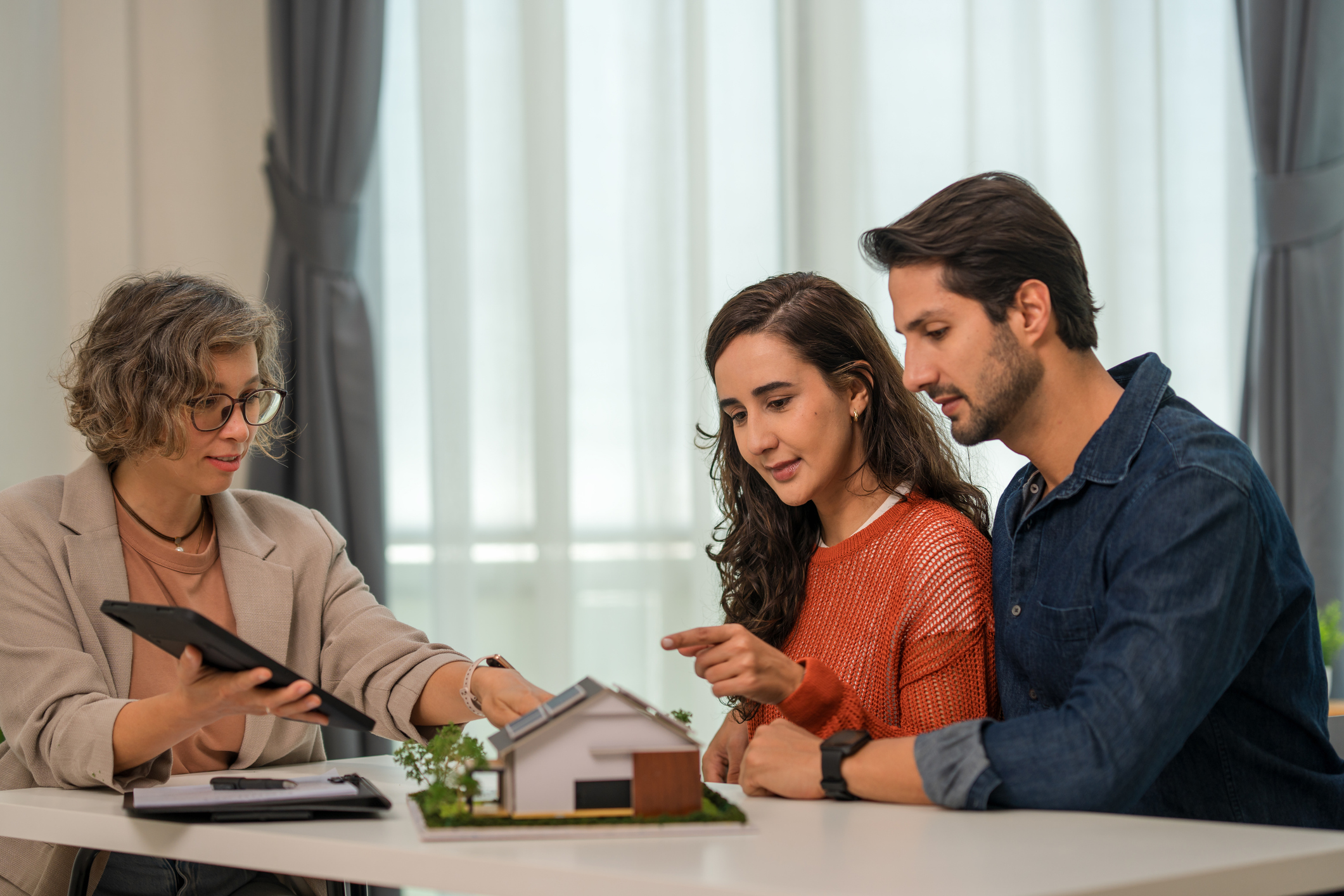 A realtor showing a couple where to sign paperwork.