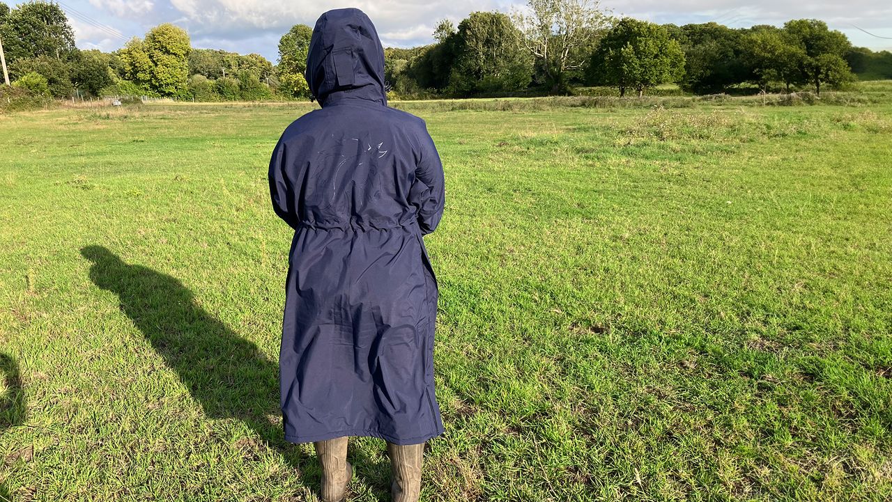 Lady wears Rydale Utility Changing Robe in a field with the hood up, viewed from the back