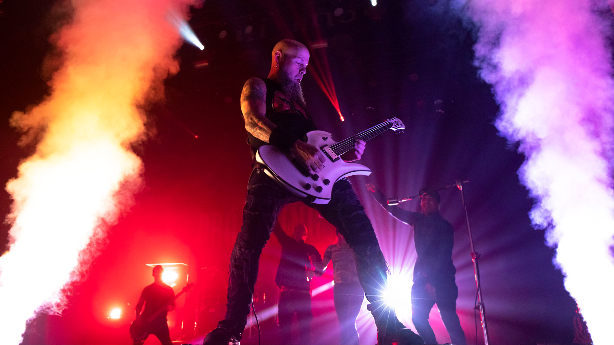 C.J. Pierce of Drowning Pool plays his white B.C. Rich Mockingbird guitar on stage, amid smoke pillars