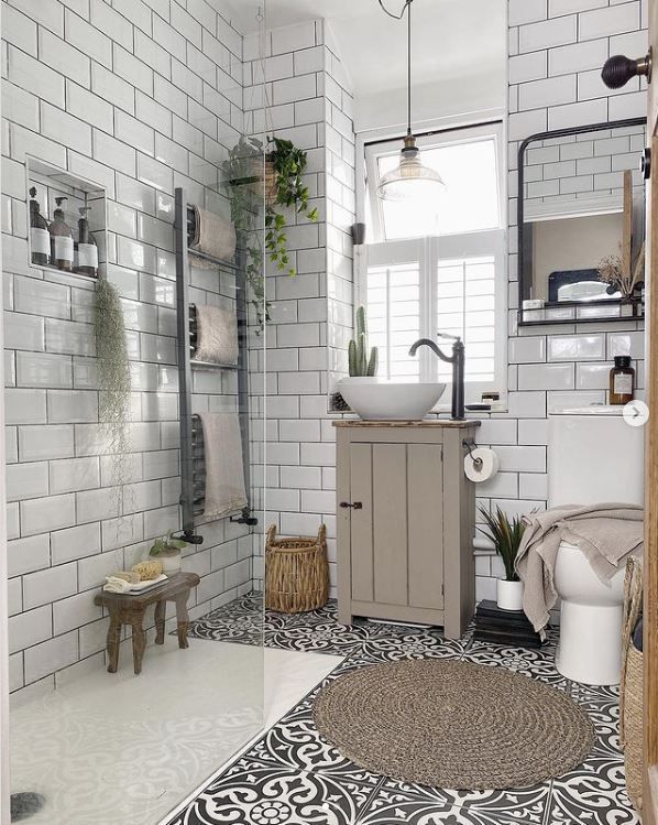 A bathroom with sink and black tap and white tiling with black grout in the shower area