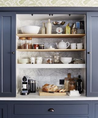 An example of small kitchen storage ideas showing a close-up shot of a storage area behind dark blue cabinet doors