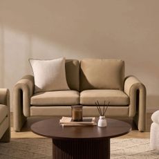 Latte coloured two seater sofa with a cream cushion and wooden coffee table in front