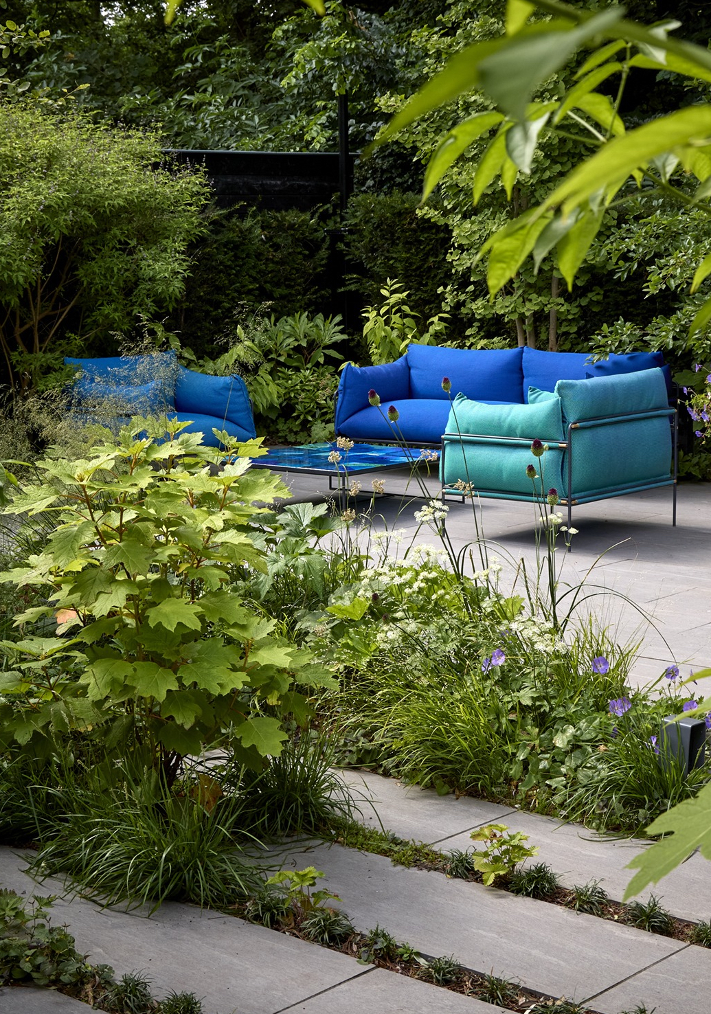 Bright blue upholstered outdoor seating in a leafy garden in The Netherlands