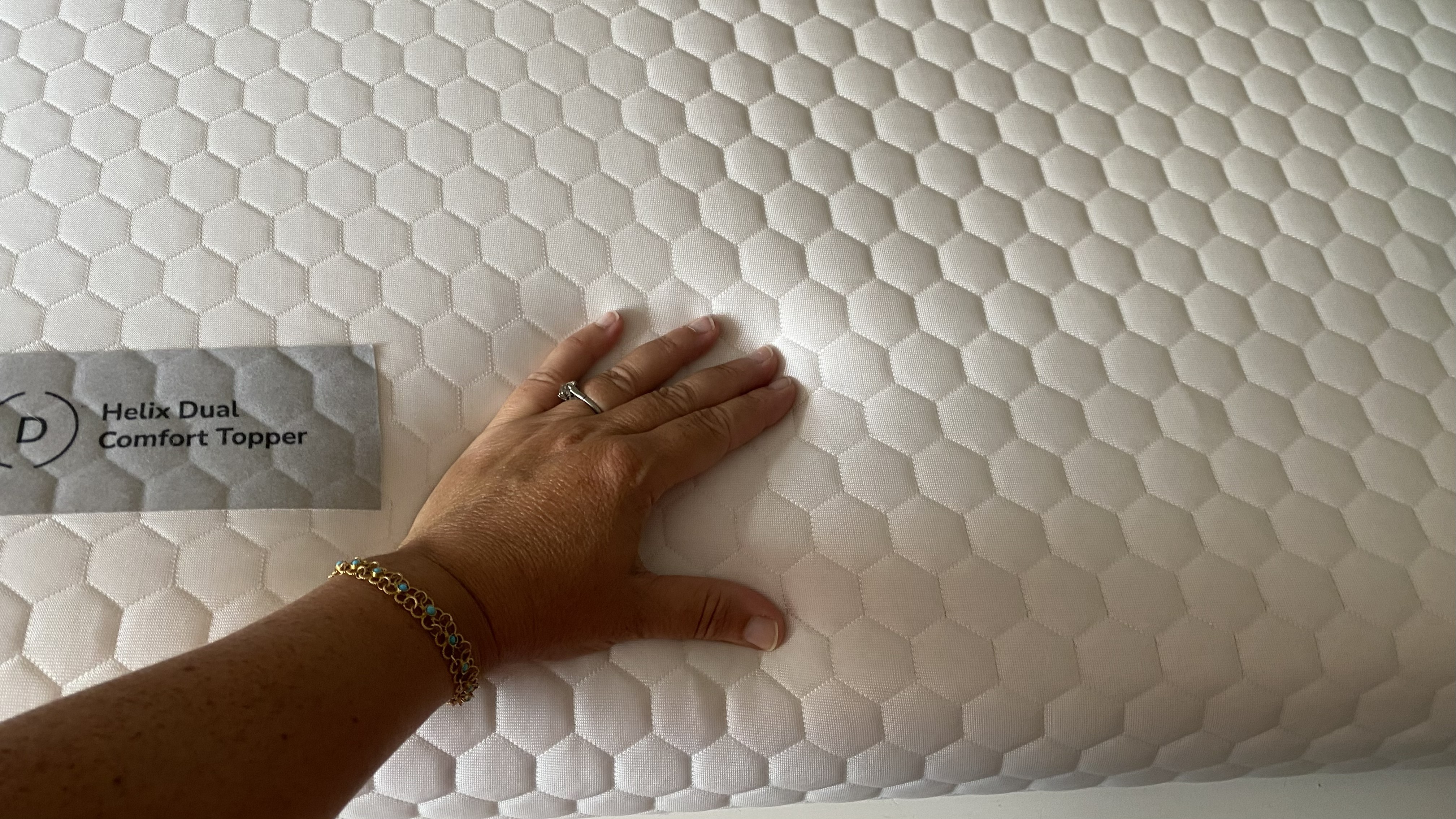 Our at-home tester feels the firmness of the Helix Dual Comfort Topper by hand.