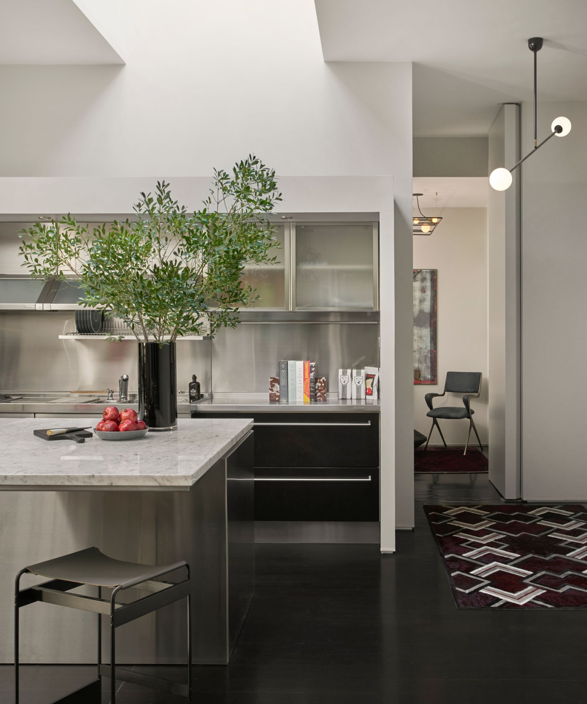 a kitchen with stainless steel countertops, an island with stone countertops, and black cabinetry