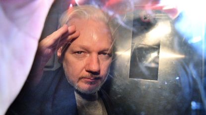 WikiLeaks founder Julian Assange gestures from the window of a prison van as he is driven out of Southwark Crown Court in London