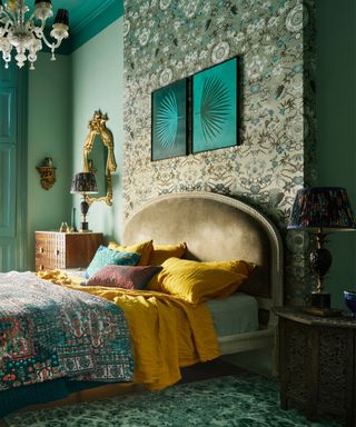 green bedroom with bold wallpaper and gold upholstered bed