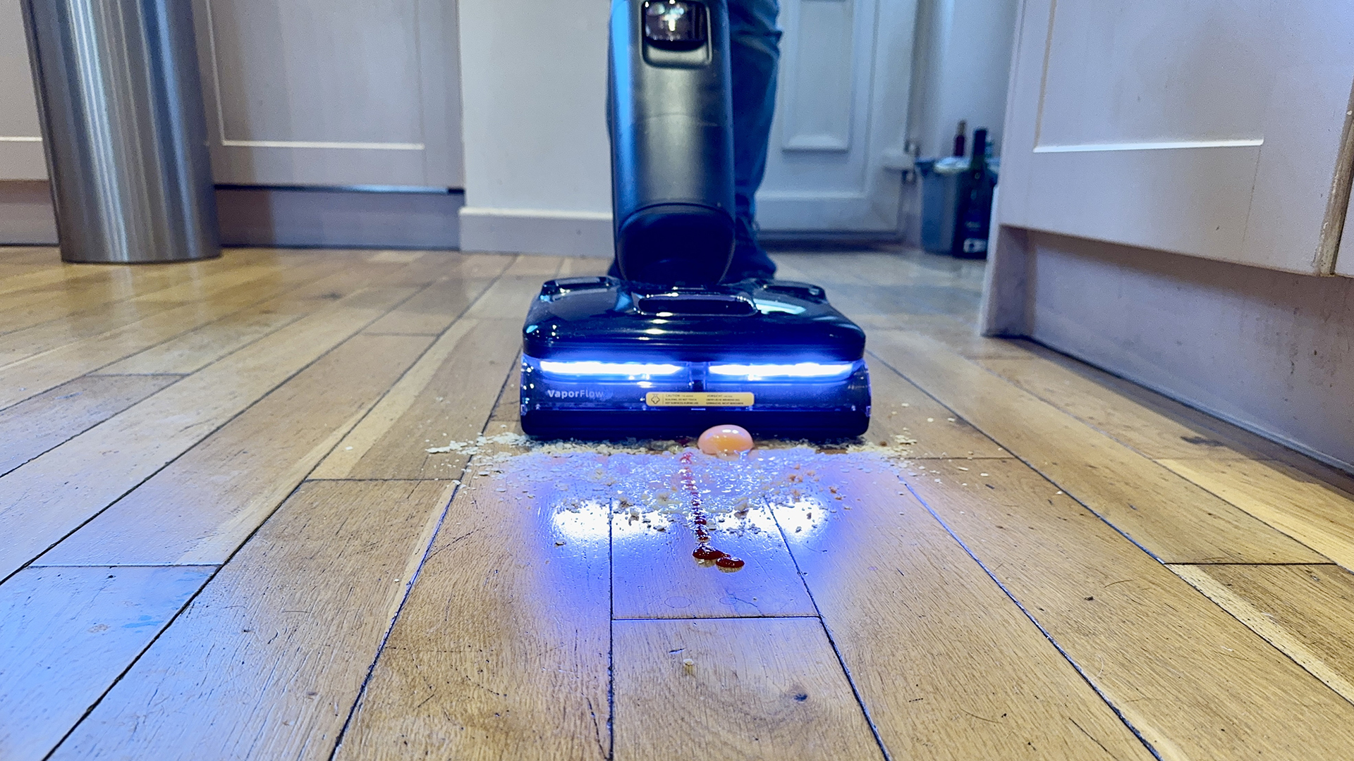 Roborock F25 Ultra clearing a mess of egg, oats, ketchup and more from an engineered wooden floor