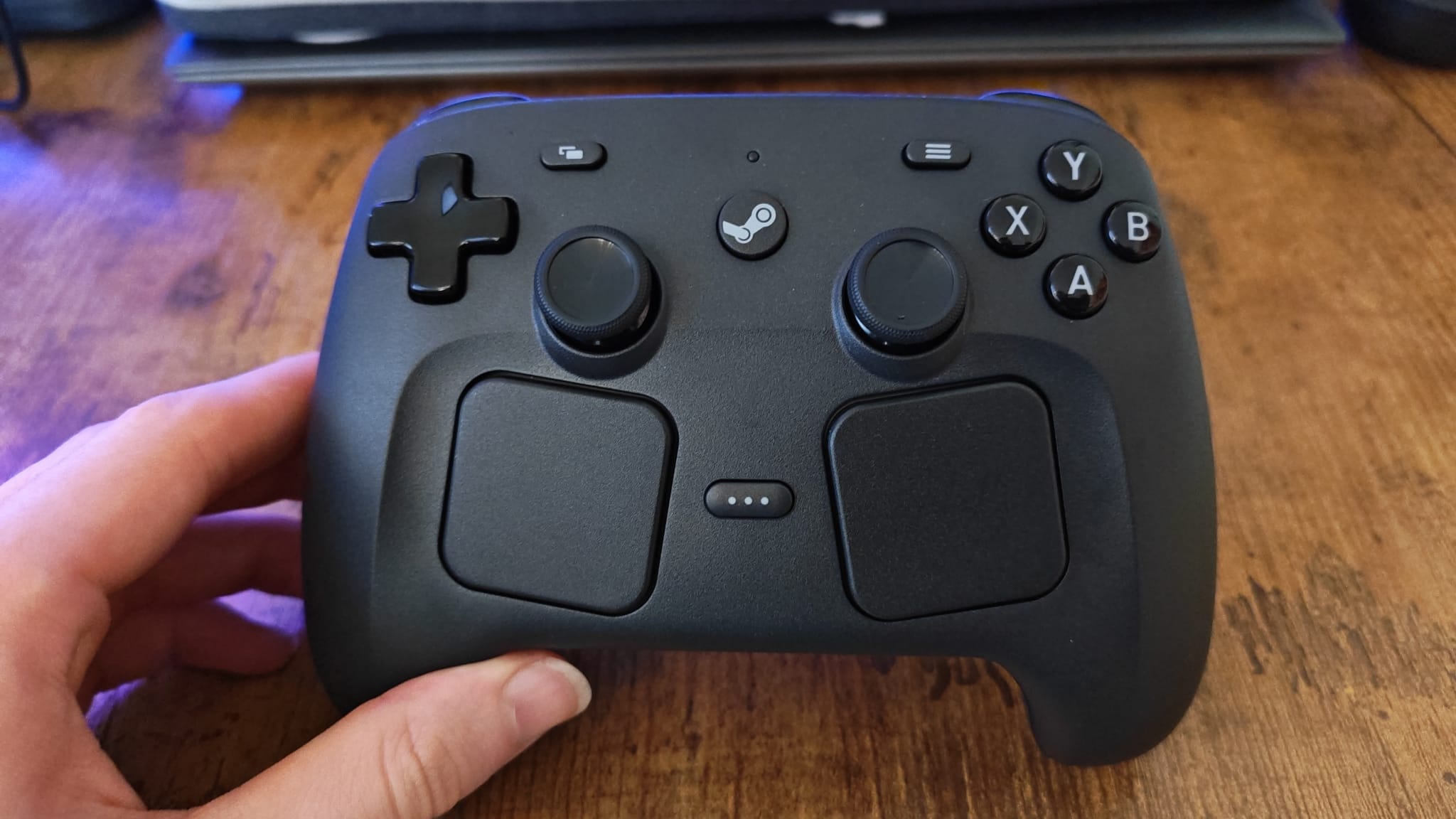 A reviewer holding up the Steam Controller to show its face to the camera