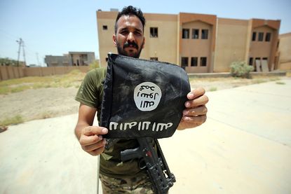 An Iraqi soldier holds an Islamic State flag after driving ISIS out of Fallujah