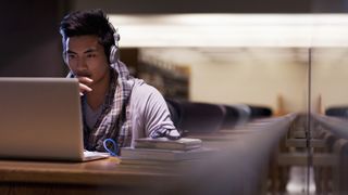 College student sat at laptop in empty classroom