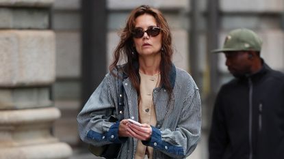 Katie Holmes wearing a navy-and-white barn jacket with camel Lafayette 148 vest and white trousers in New York City May 2024