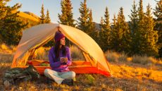 A woman camping outdoors in the evening