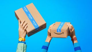 Two pairs of hands holding up Amazon delivery boxes with blue Prime Day tape wrapped around them