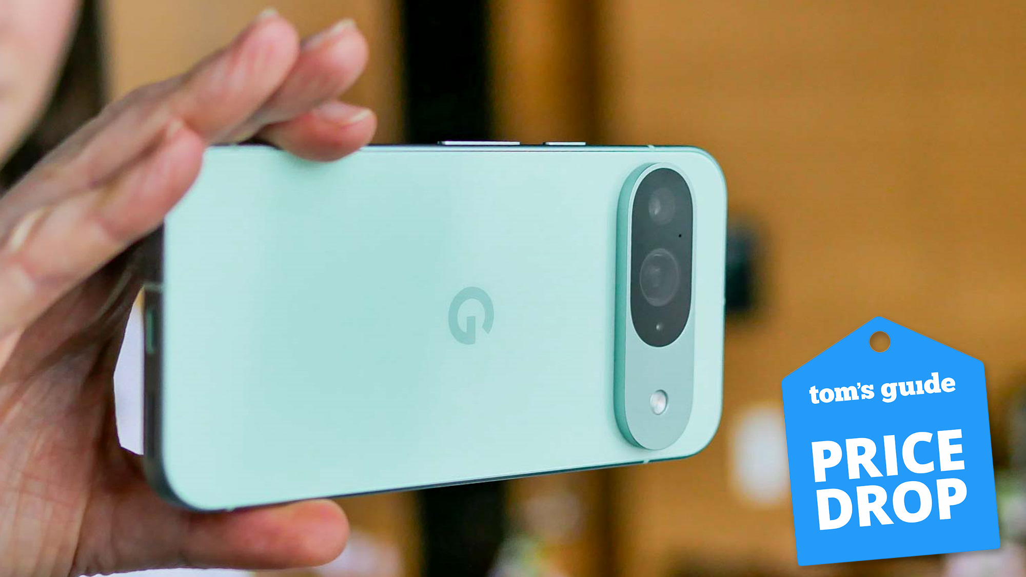 Pixel 9 held in the hand with price drop badge nearby.