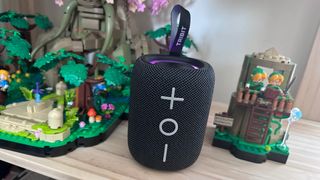 Tribit Stormbox Mini Plus Bluetooth speaker beside two Lego structures, on a wooden surface