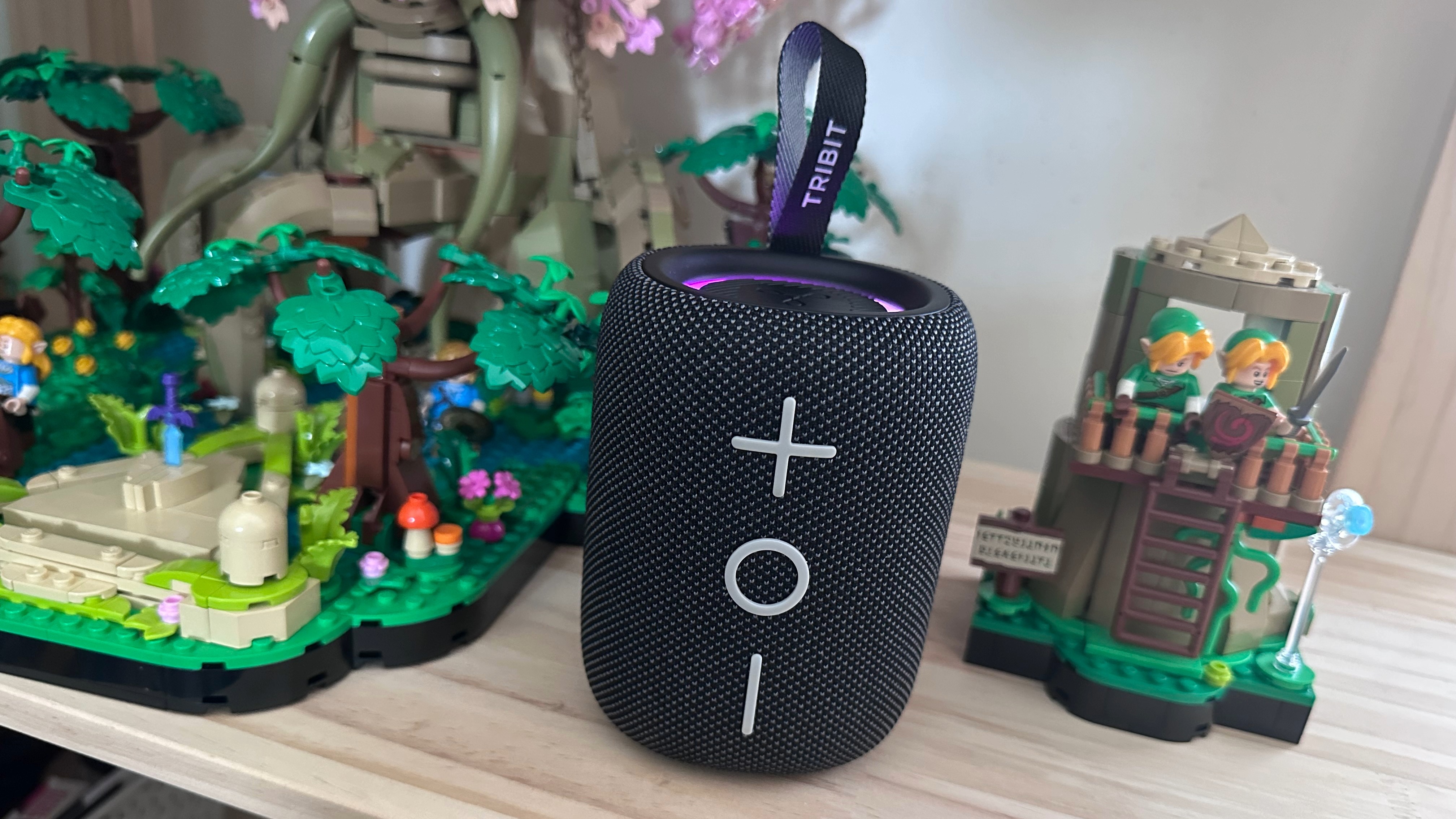 Tribit Stormbox Mini Plus Bluetooth speaker beside two Lego structures, on a wooden surface