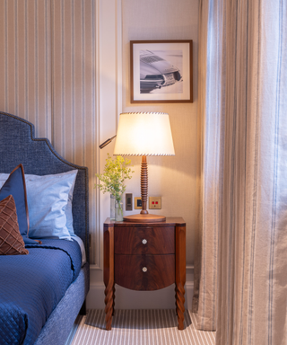 Lamp shade on night stand in classic bedroom with blue textiles and mixed materials