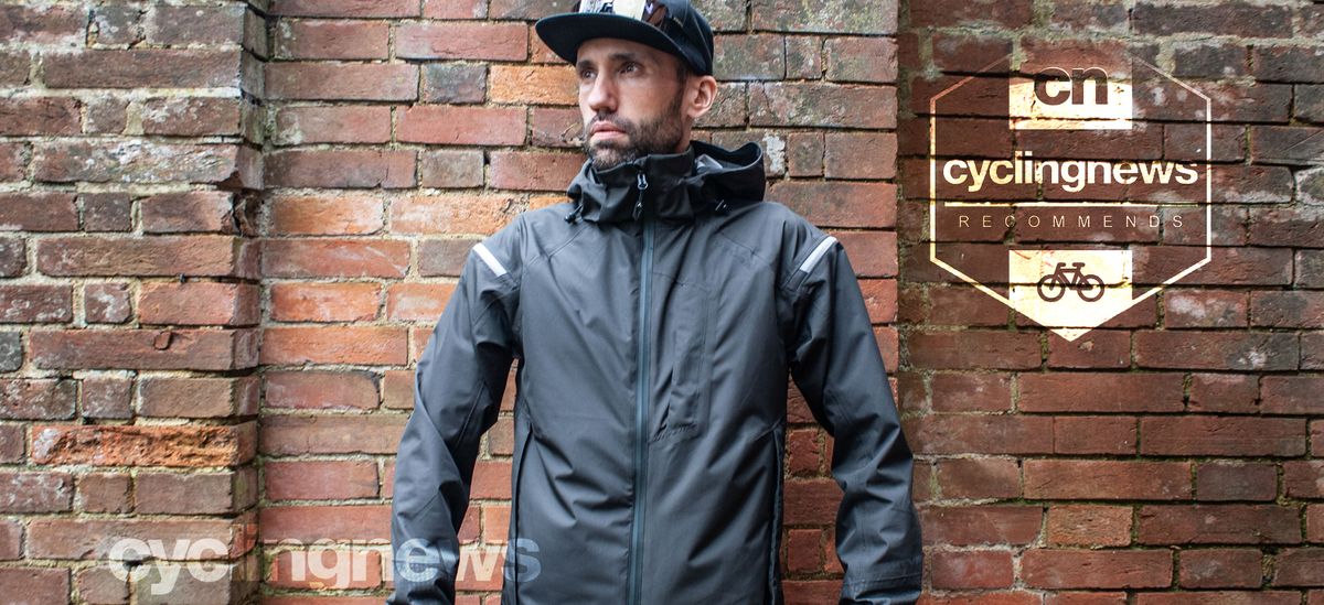 Aaron wearing the carbon grey Altura Nightvision Electron jacket, whilst stood in front of a brick wall - image is overlaid with a &#039;recommends&#039; badge