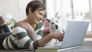 woman smiling looking at laptop with white terrier