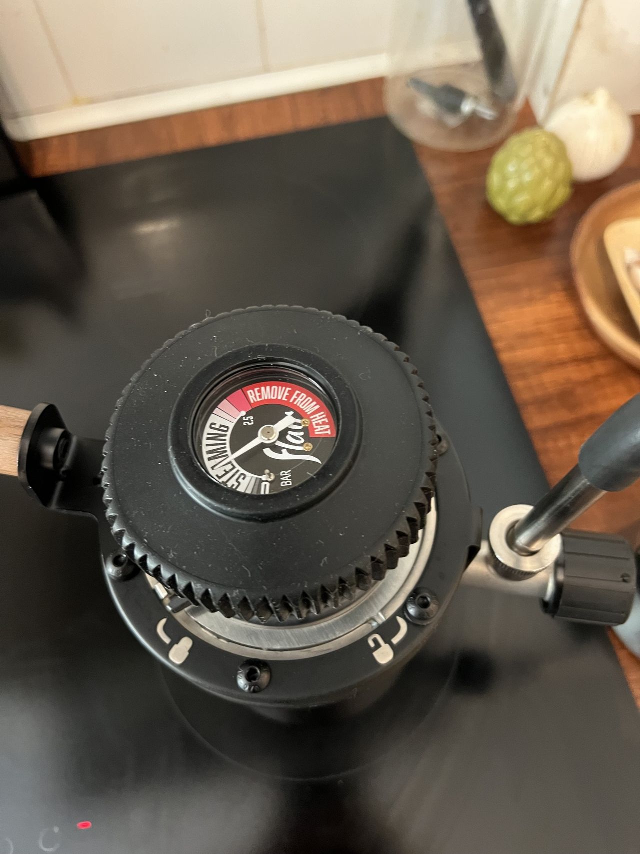 Overhead view of a black stovetop milk steamer on a black hob.