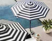 A black and white striped patio umbrella by the poolside