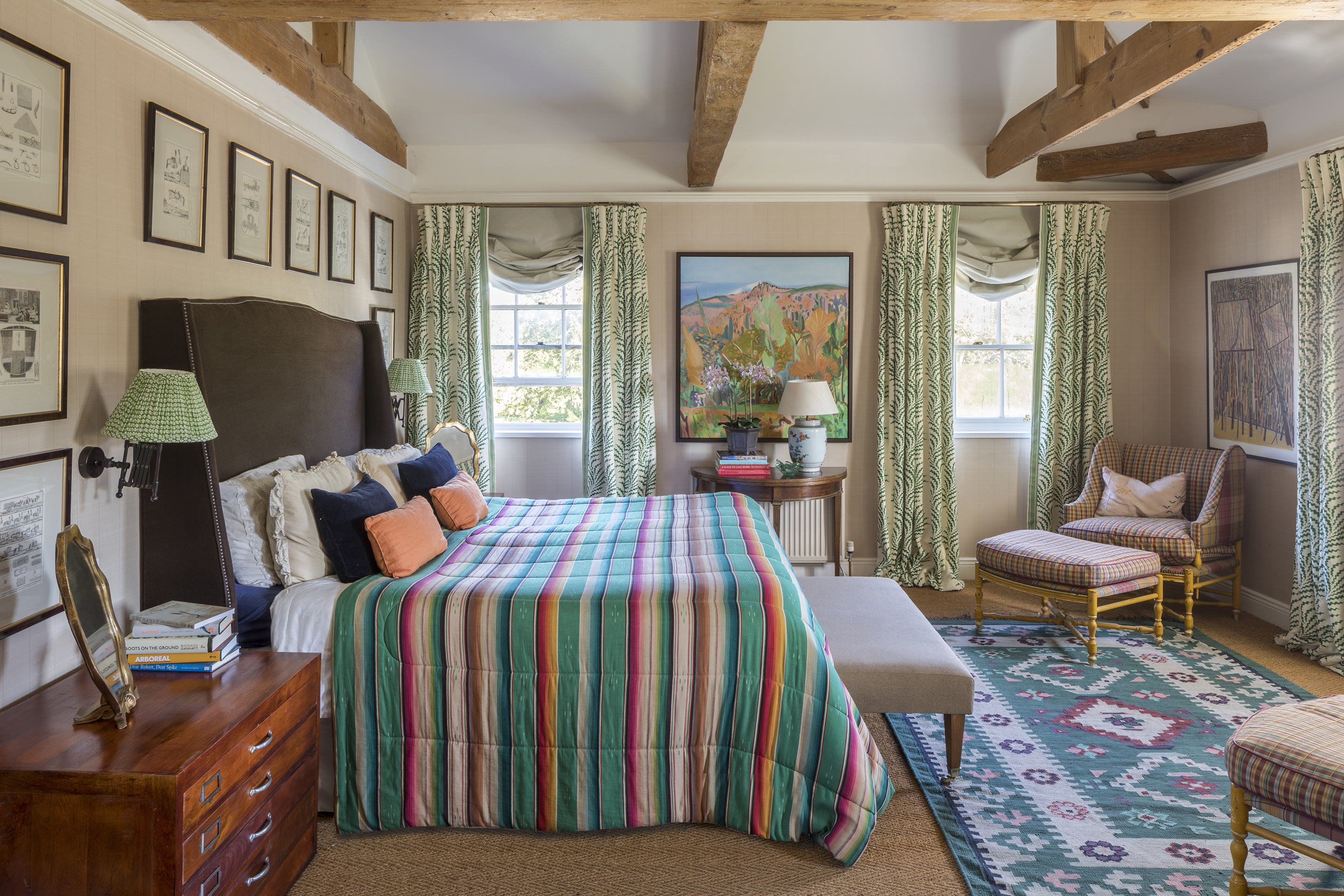 bedroom with double bed with upholstered headboard, armchair and stool and rug on floor