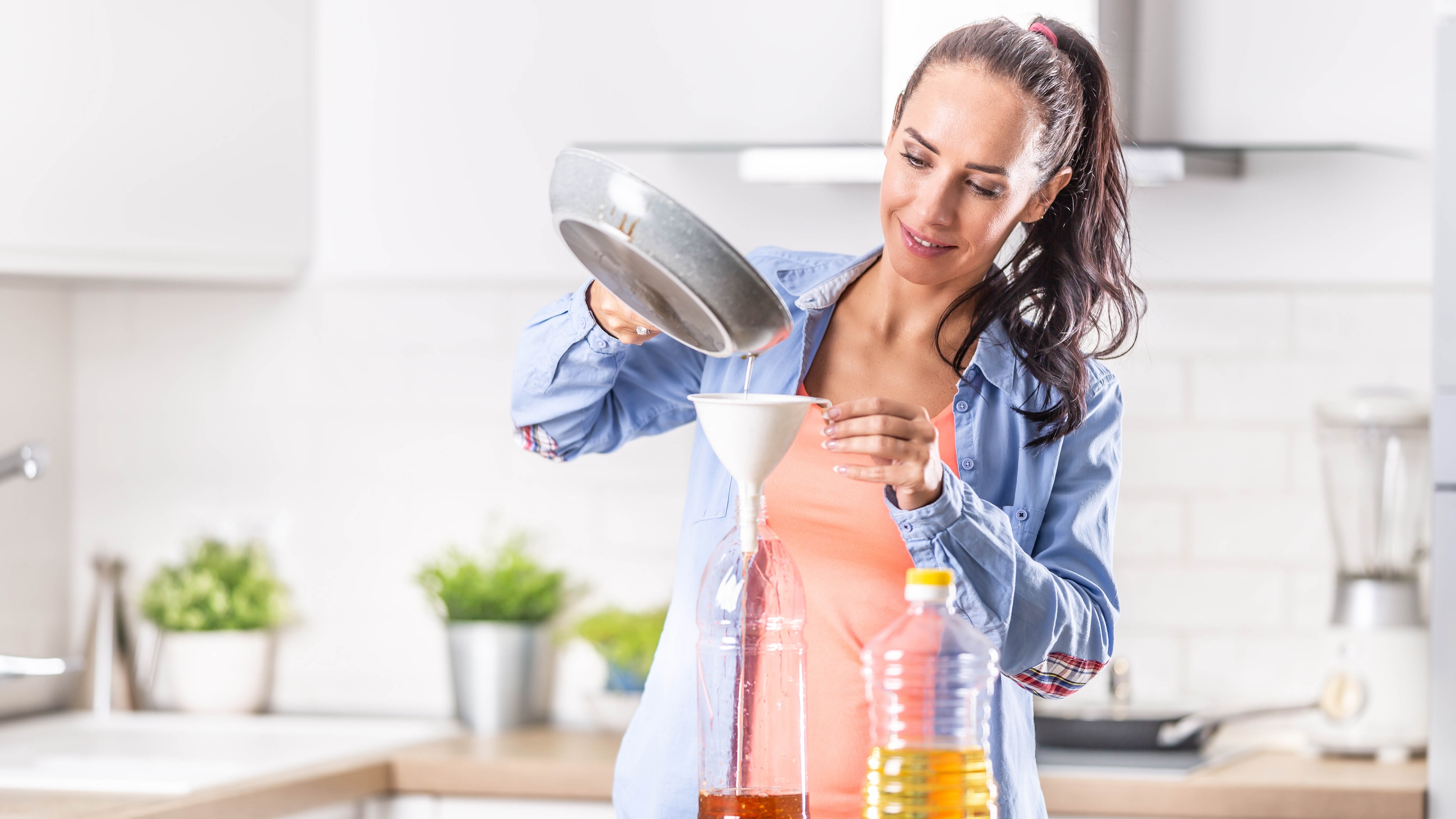 Woman pours oil into the bottle with a funnel