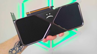Hand holding RTX 5070 graphics card with sad text face at top.