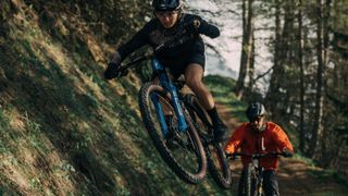 A woman does a jump on a mountain bike trail