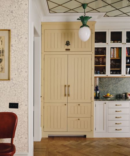A kitchen larder painted in straw yellow paint