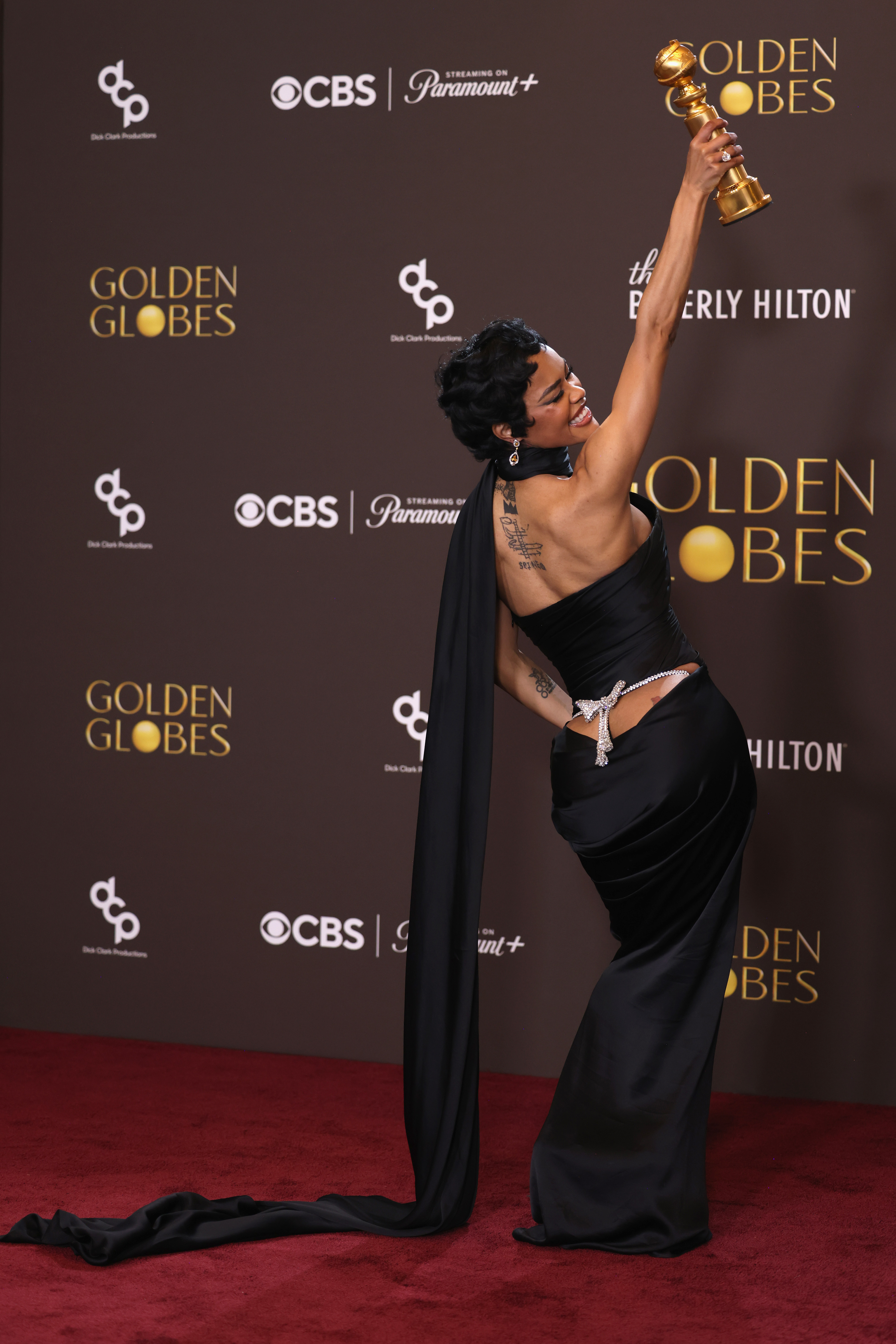 Teyana Taylor arrived at the Schiaparelli couture show in a lace little black dress, a crown, and a bow necklace inspired by her golden globes back