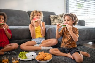 children having an indoor picnic eating fruit