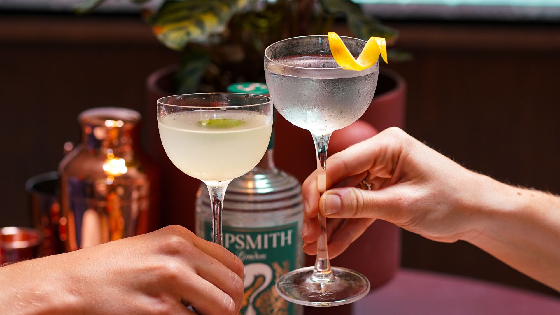 an image of two round martini glasses being 'cheers'd' over a central table with picky bits on plates.  