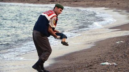 A Turkish police officers carries the dead body of Aylan Kurdi