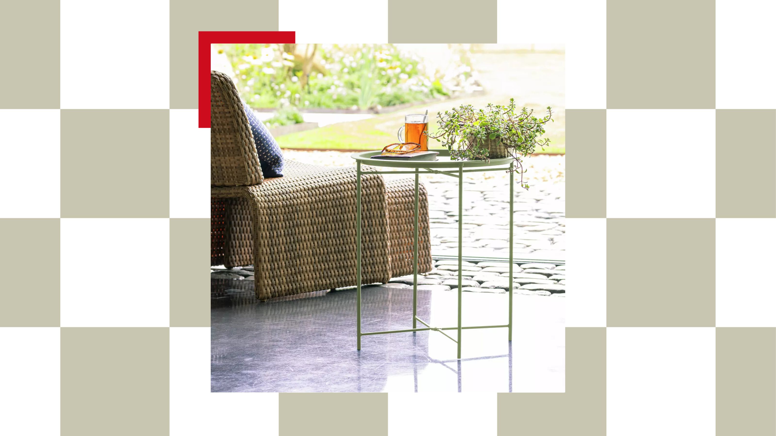 Habitat's folding green metal garden side table with a plant, drink, and snack on top next to its rattan-effect outdoor lounge chair