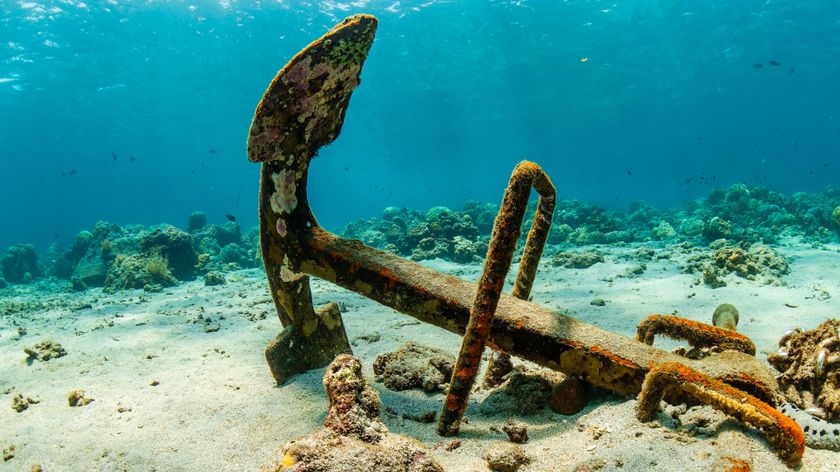 Large anchor on a sandy seafloor next to a coral reef in Asia