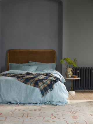 bedroom with a bed with light blue linen sheets and tartan throw over the top