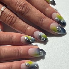 An image of sage green nails with metallic 3D accents.