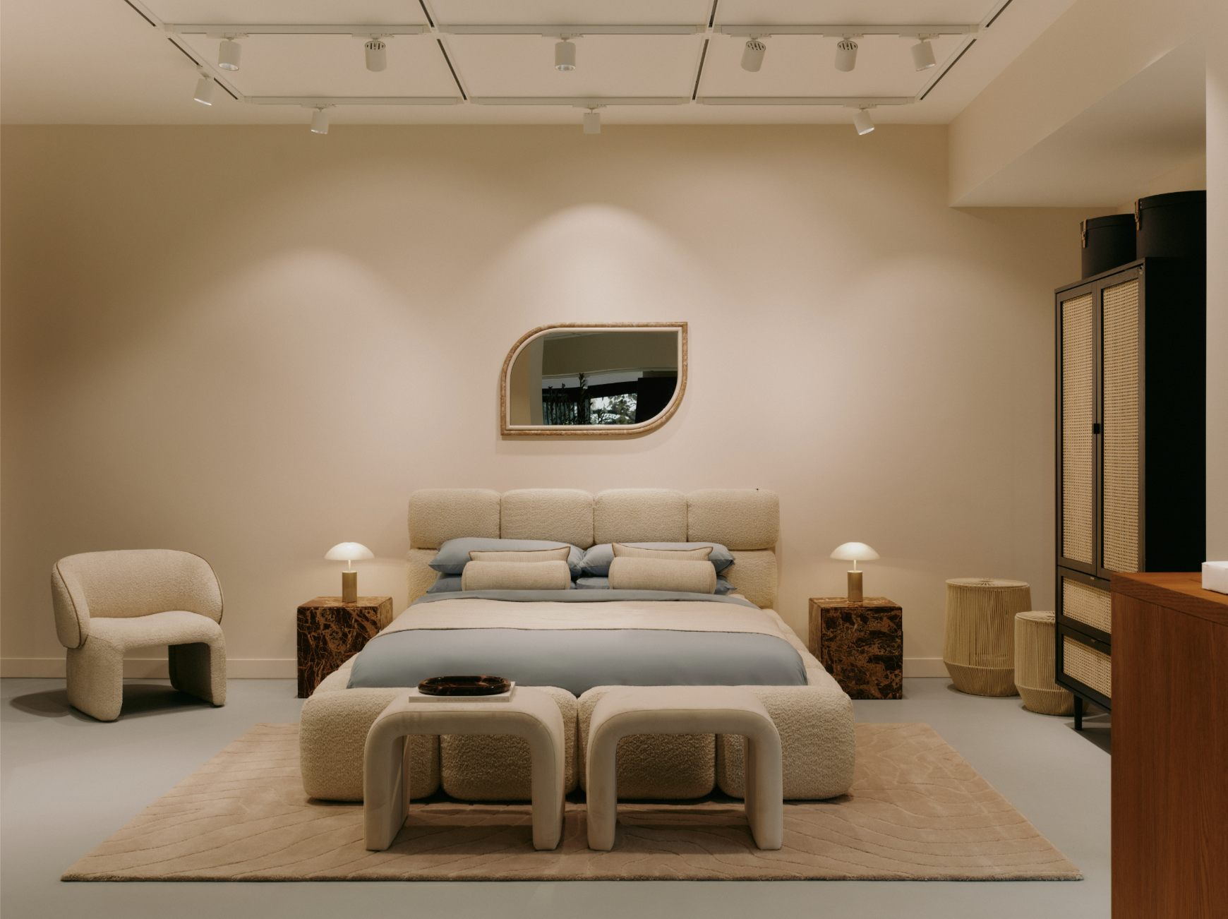 Image of a modern beige upholstered bed with light blue and beige bedding in a bedroom with beige walls and a light blue floor.