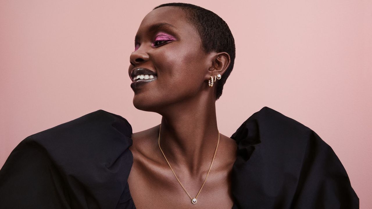 A woman smiling looking to the side wearing pandora jewellery 